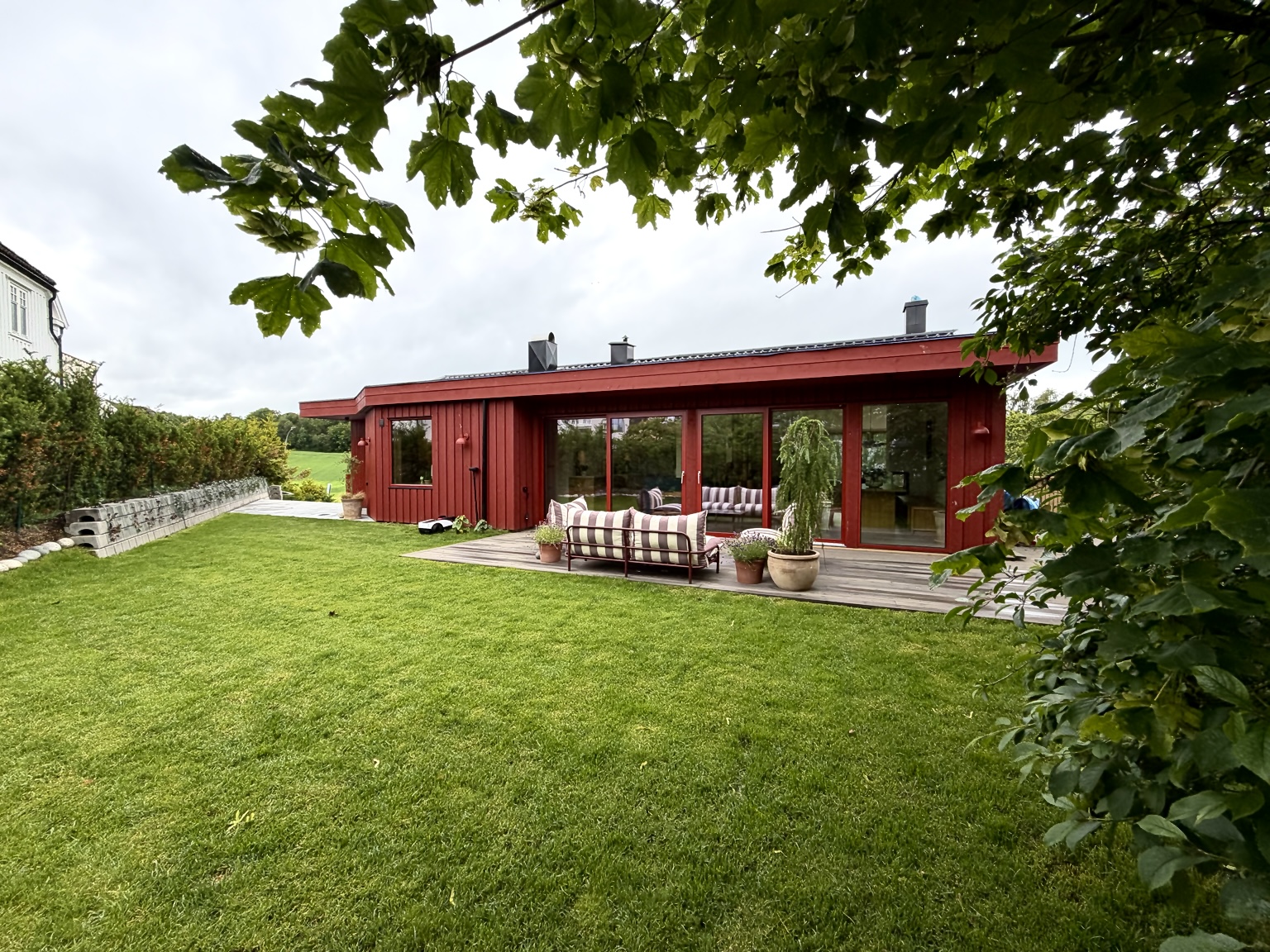 Det røde huset på Fagerheim Allé 89b, med hage og store vinduer.